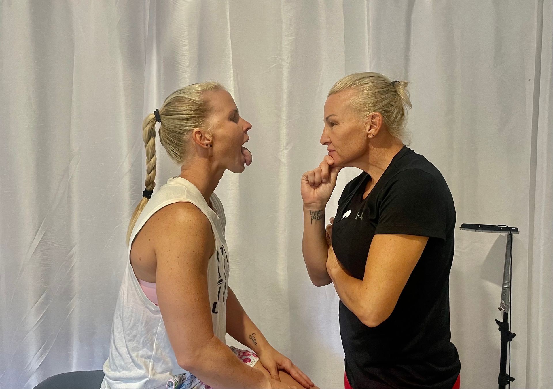 Woman looking into another woman's mouth to analyse her tongue. Traditional Chinese Medicine tongue diagnosis.